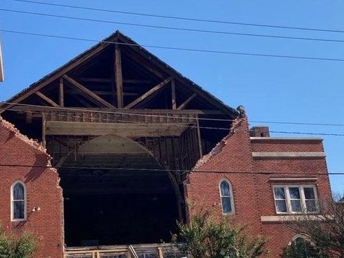 Brick building with a collapsed gable wall and exposed roof framing
